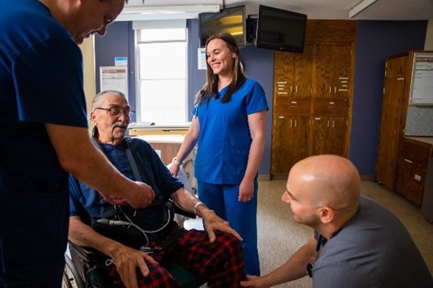 Inpatient care team rehabilitation experts help patient in wheelchair.