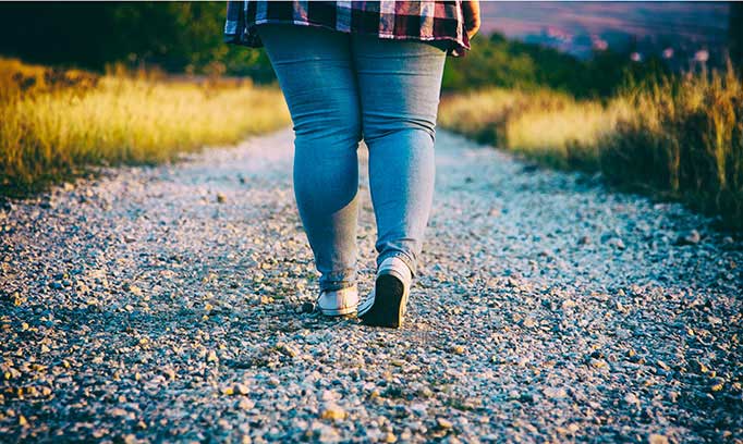 jean-clad legs walking down gravel path near sunset