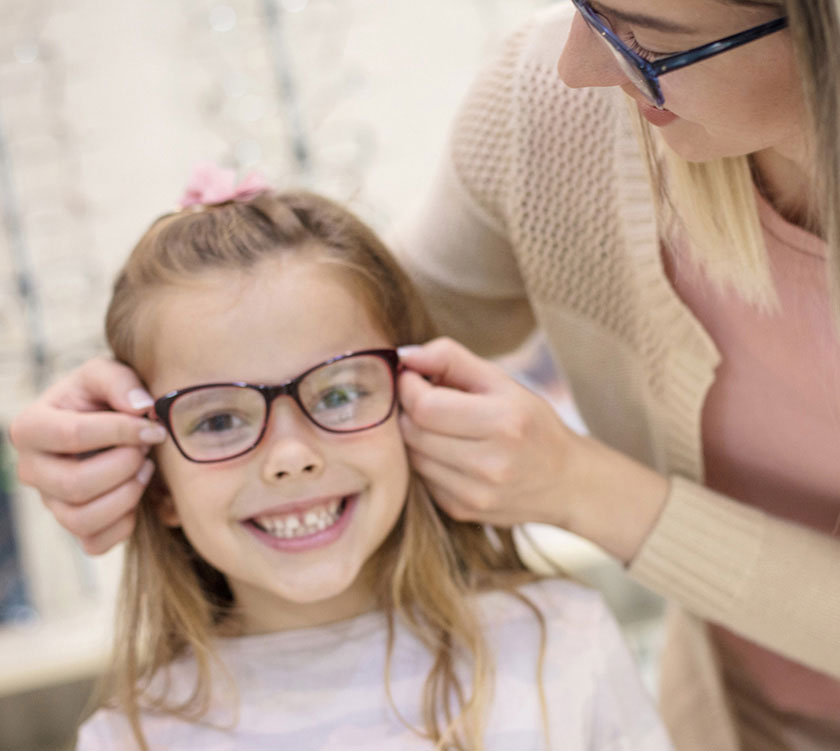 Optician with young girl during eyeglass fitting