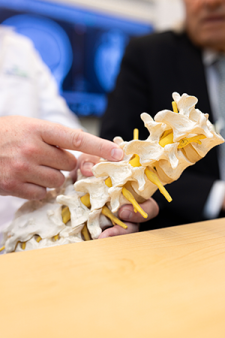 Caregiver pointing at a portion of a spine model